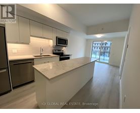 A kitchen with a refrigerator, microwave, and stove top oven.