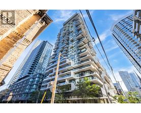 A modern glass building stands tall among other buildings in a cityscape.
