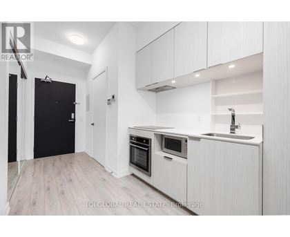 A modern kitchen with white cabinets and a black door.