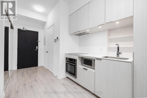 A modern kitchen with white cabinets and a black door.