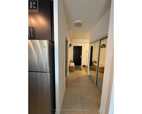 A hallway with a black door and a white wall.