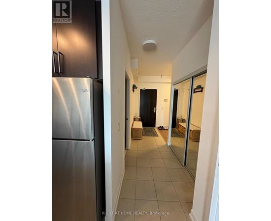 A hallway with a black door and a white wall.