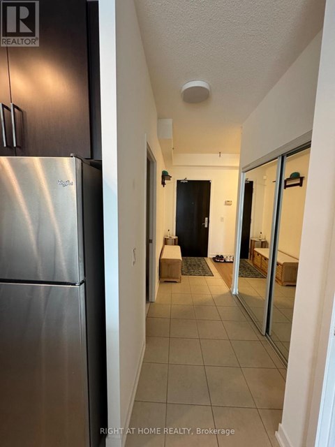 A hallway with a black door and a white wall.