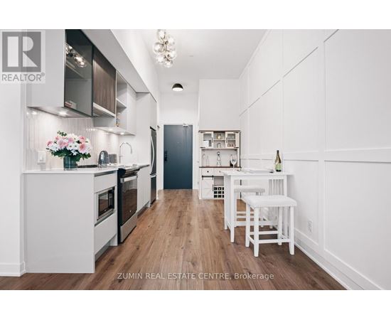 A modern kitchen with white cabinets and a wooden floor.