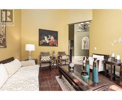 A living room with a couch, chairs, and a painting on the wall.