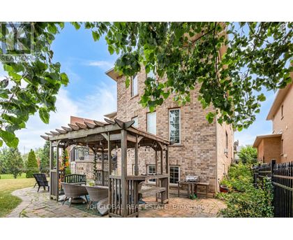 A gazebo is situated in a backyard with a patio and a brick house.
