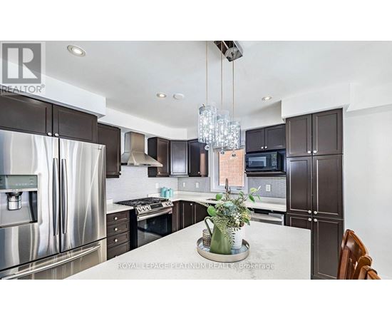 A modern kitchen with a stainless steel refrigerator and dark brown cabinets.