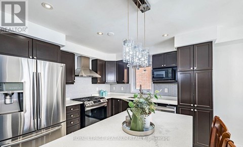 A modern kitchen with a stainless steel refrigerator and dark brown cabinets.