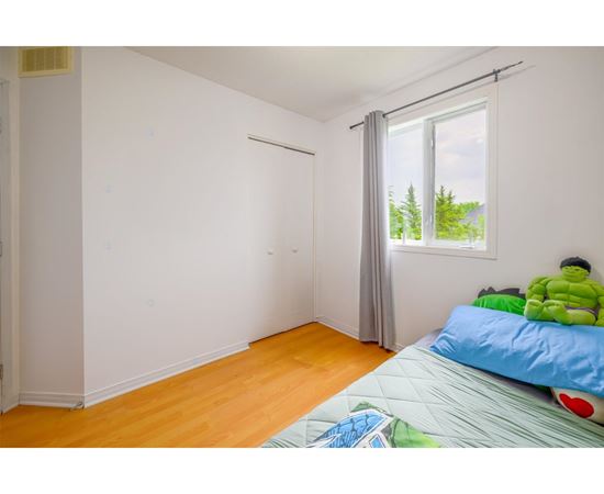 A room with a bed and a window with a view of trees.