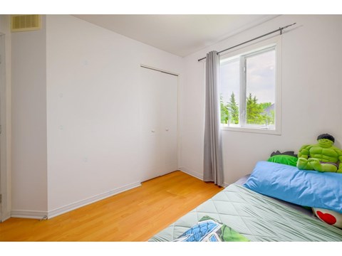 A room with a bed and a window with a view of trees.