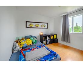 A bedroom with a bed covered in a blue and red comforter and a picture frame on the wall.