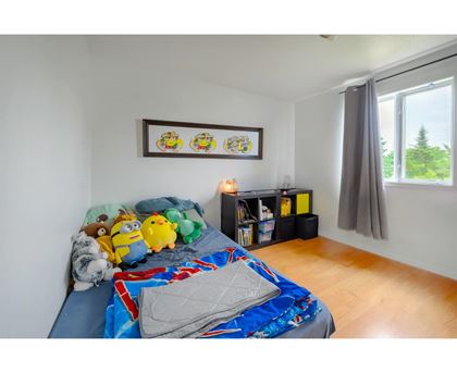 A bedroom with a bed covered in a blue and red comforter and a picture frame on the wall.