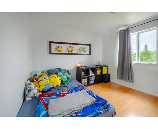 A bedroom with a bed covered in a blue and red comforter and a picture frame on the wall.