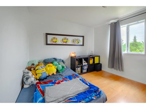 A bedroom with a bed covered in a blue and red comforter and a picture frame on the wall.