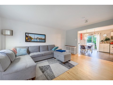 A living room with a grey sofa and a painting on the wall.