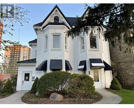 A white house with a black roof and a sign that says "Royal LePage Triland Realty, Blokarage.".