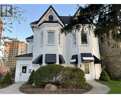A white house with a black roof and a sign that says "Royal LePage Triland Realty, Blokarage.".