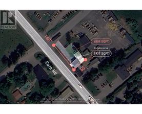 An aerial view of a street with a building and a carport on the right side.