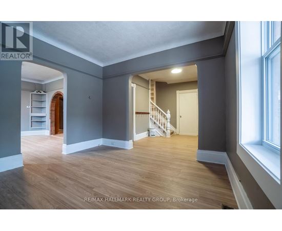 A spacious room with wooden floors and a staircase leading to another room.