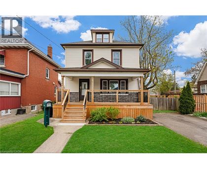 A house with a white siding and a brown roof with a deck in front.