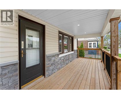 A wooden deck leads to a house with a stone wall and a glass door.