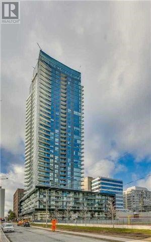 A tall blue building under construction with a cloudy sky in the background.