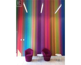 Two purple chairs and two white tables in front of a colorful striped wall.