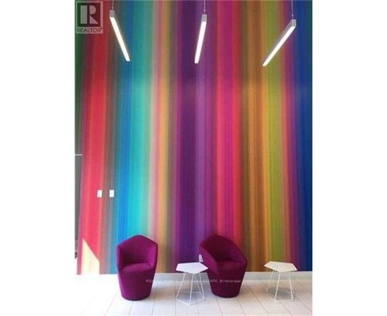 Two purple chairs and two white tables in front of a colorful striped wall.
