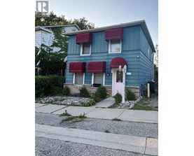 A blue house with a pink door and red awnings.