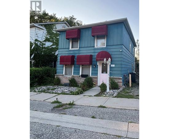 A blue house with a pink door and red awnings.