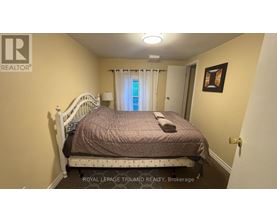 A bedroom with a bed, a window with curtains, and a picture on the wall.