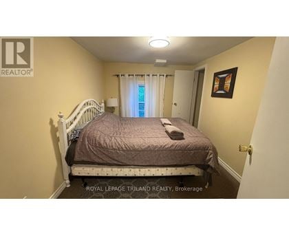 A bedroom with a bed, a window with curtains, and a picture on the wall.