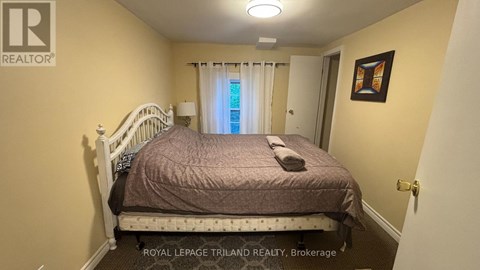 A bedroom with a bed, a window with curtains, and a picture on the wall.