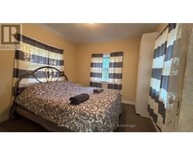 A bedroom with a patterned bedspread and striped curtains.