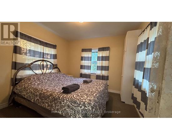 A bedroom with a patterned bedspread and striped curtains.