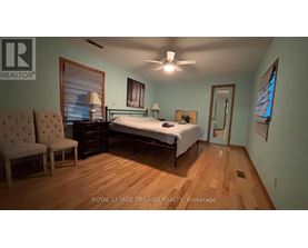 A bedroom with a bed, chair, and a ceiling fan.