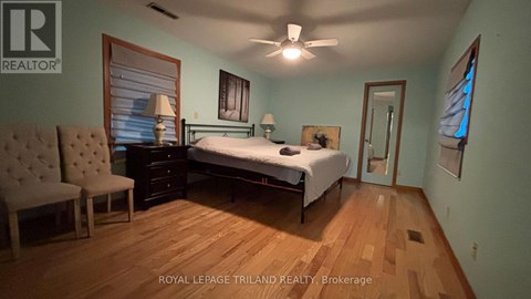 A bedroom with a bed, chair, and a ceiling fan.