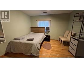 A bedroom with a bed, nightstand, and chair.