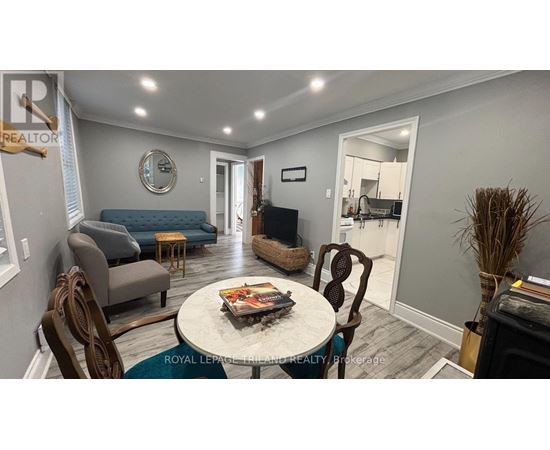 A living room with a grey couch, a round table with a magazine on it, and a mirror on the wall.