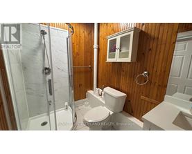 A bathroom with a glass shower stall and a toilet.