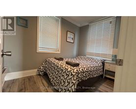 A bedroom with a bed, nightstand, and window with blinds.