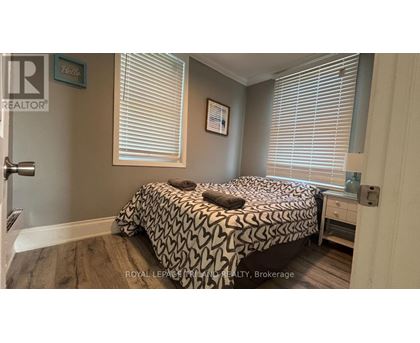 A bedroom with a bed, nightstand, and window with blinds.