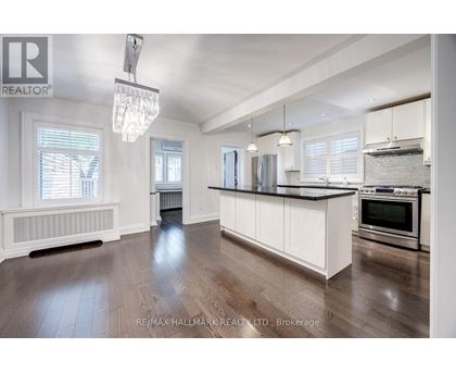 A spacious kitchen with white cabinets and a wooden floor.