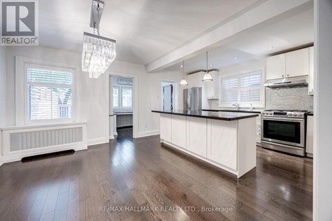 A spacious kitchen with white cabinets and a wooden floor.