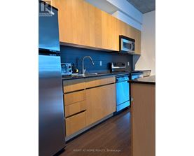 A kitchen with wooden cabinets and a stainless steel refrigerator.