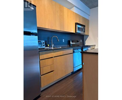 A kitchen with wooden cabinets and a stainless steel refrigerator.