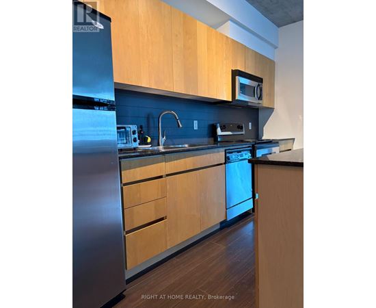 A kitchen with wooden cabinets and a stainless steel refrigerator.