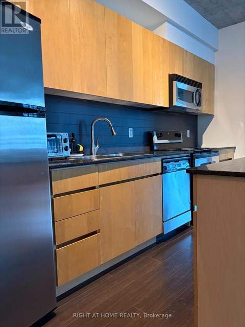 A kitchen with wooden cabinets and a stainless steel refrigerator.