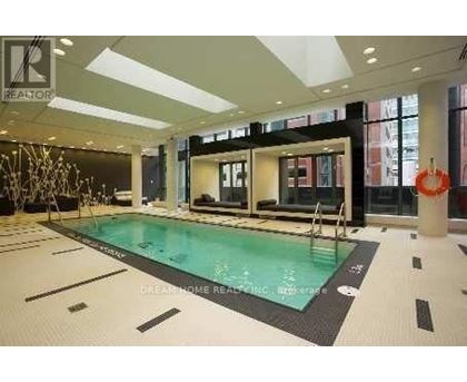 A swimming pool inside a building with a glass wall.