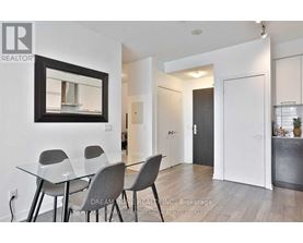 A dining room with a glass table and grey chairs.